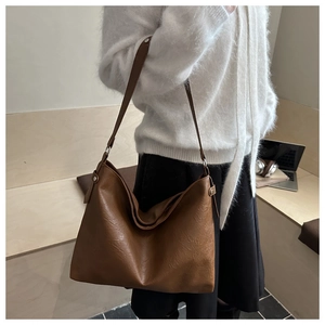 Detail view of large brown Hobo bag in textured vegan leather worn by a model