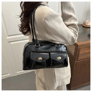 Details einer schwarzen glänzenden Schultertasche mit zwei Vordertaschen und Golddrehverschlüssen