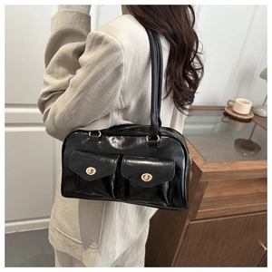 Details einer schwarzen Lackleder-Achseltasche mit zwei goldenen Drehverschluss-Taschen