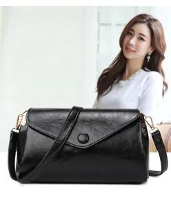 Close-up of black glossy leather square bag with V-shaped flap and metallic hook detail