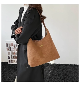 Détail du sac fourre-tout en daim camel avec logo doré et large bandoulière intégrée