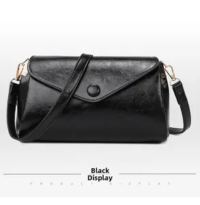 Detail of black envelope crossbody bag showing oil skin texture and golden metal hardware