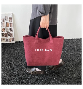 Detailed close-up of dark red suede tote bag with white TOTE BAG embroidery text