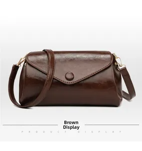 Detail of dark brown leather shoulder bag with glossy finish and gold metal buckle