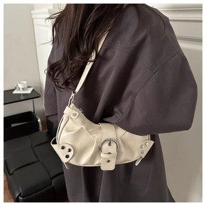 Detail of cream hobo bag featuring silver buckle and studs on soft faux leather