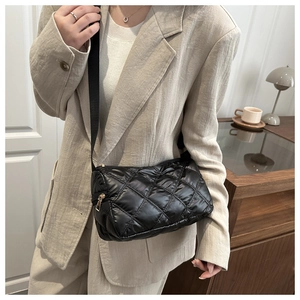 Detailed close-up of a black quilted puffer crossbody bag with elegant gold zipper accents