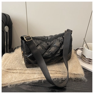 Detailed close-up of black quilted nylon bag with golden metal buckles and adjustable strap
