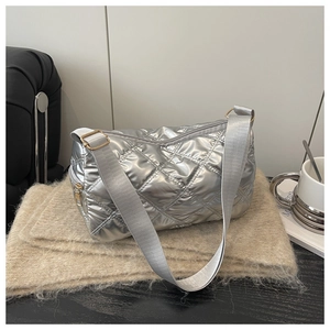 Macro shot of silver quilted shoulder bag texture with glossy metallic finish and strap