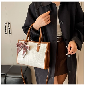 Détail du sac cabas crème motif serpent avec poignées marron et foulard en soie à cœurs