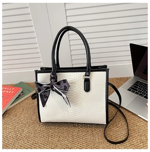 Detailansicht der Handtasche mit Schlangenmuster-Prägung und dekorativem Seidenschal