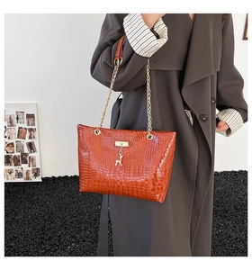 Detail of reddish-brown croc-pattern bucket bag with gold chain and deer charm