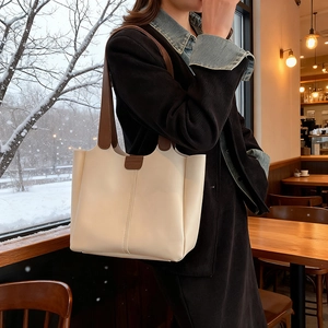 Minimalist beige and brown two-tone large capacity tote bag shown in cozy cafe setting