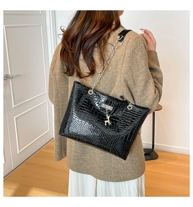 Close-up of black crocodile pattern tote bag with silver deer pendant and chain strap