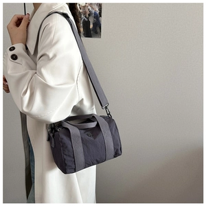 Grey canvas crossbody bag worn with a casual coat, showcasing the compact size and style