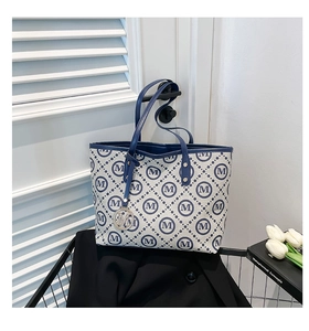Détail de l'anse en cuir bleu et du pendentif M sur le sac cabas en toile à motif