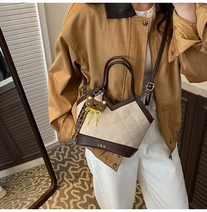 Detailed shot of two-tone bucket bag with quilted patterns and a cute bear charm