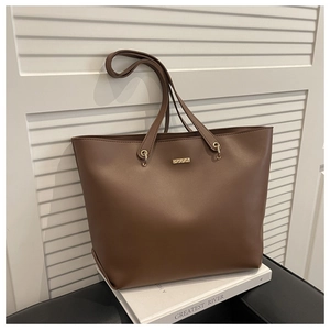 Détail d'un grand sac cabas en cuir mat marron avec plaque dorée et anneaux en métal