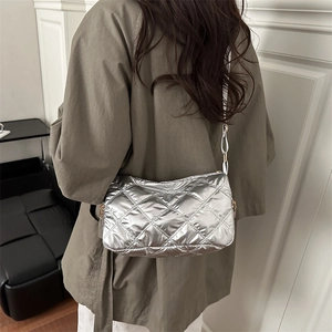 Silver quilted crossbody bag with metallic finish shown on model in a minimalist setting