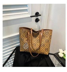 Détail d'un cabas marron à monogramme avec pendentif M argenté et cuir fin