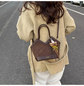 Detail view of brown suede handbag with V-cut design and cute teddy bear pendant