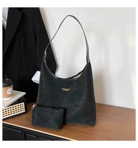 Detail of black matte leather tote bag with matching zipper pouch and gold lettering