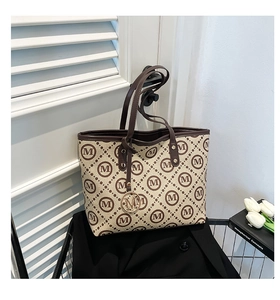 Détail du sac cabas monogramme avec bordure en cuir marron et pendentif M en métal