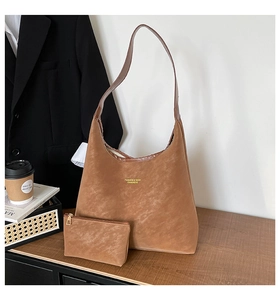 Brown leather tote bag and small pouch on wooden desk with coffee and blazer