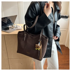 Detail of vintage coffee brown frosted tote bag with plush bear charm and long shoulder strap