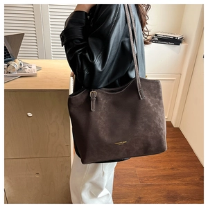Close-up of a large leather tote bag with gold lettering and long shoulder straps
