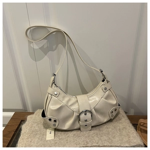 Close-up of beige crescent bag with silver buckle, rivets, and pleated faux leather texture