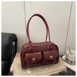 Détail d'un sac à bandoulière en cuir ciré rouge foncé avec deux poches et fermoirs dorés