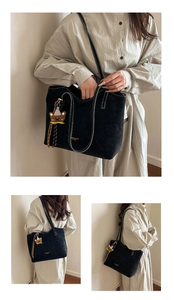 Detail of black matte tote bag with bear charm and contrast stitching on shoulder straps