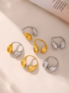 Polished teardrop-shaped open rings in gold and silver finish on a neutral surface