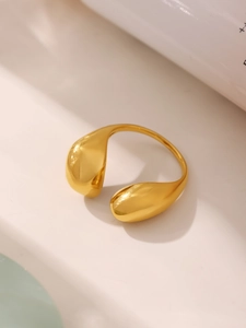 Macro detail of golden teardrop-shaped open ring showing polished finish and sleek metal