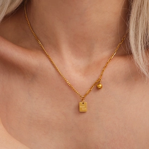 Collana asimmetrica in acciaio placcato oro con ciondolo Good Luck indossata da modella