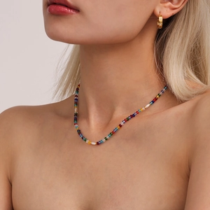 Colorful beaded necklace with pearls and gold hoop earrings on a fashion model