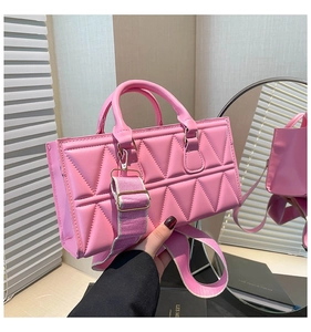 Detail of pink quilted handbag showing geometric triangular texture and woven shoulder strap