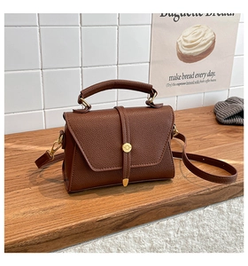 Detail of dark brown lychee textured leather crossbody bag with golden hardware