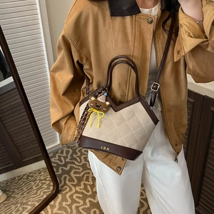 Women's beige quilted suede handbag with brown leather trim and bear pendant