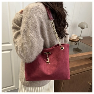 Détail du sac cabas en daim bordeaux avec bandoulière chaîne dorée et pendentif cerf
