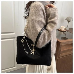 Détail du sac cabas en daim noir avec chaîne en métal et pendentif cerf sur un mannequin