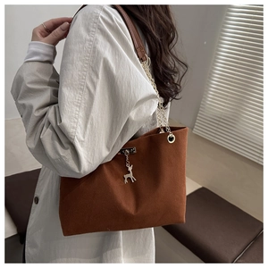 Gros plan du sac cabas marron avec bandoulière chaîne dorée et pendentif cerf