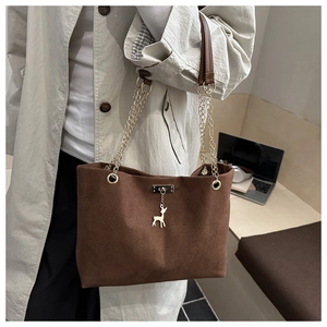 Sac fourre-tout marron foncé avec chaîne dorée et pendentif cerf porté par le mannequin