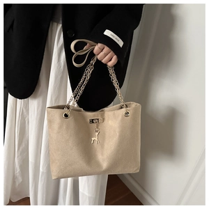 Détail du sac beige mat avec doubles chaînes dorées et pendentif cerf élégant