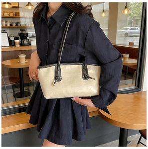 Detail of minimalist beige leather tote bag with black knotted handles on a cafe table
