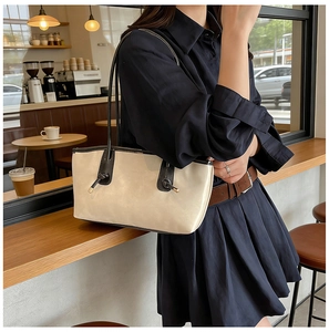 Chic cream tote bag with black knotted straps shown in a cozy cafe setting