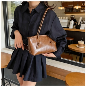 Close-up of brown vintage PU leather shoulder bag with knot detail in a cafe setting