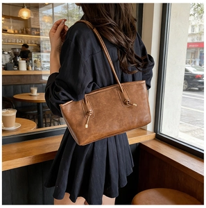 Detail of retro brown leather tote bag featuring elegant knotted straps and metal accents