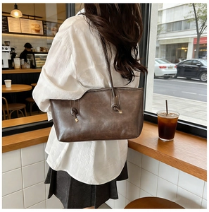 Detail of dark brown vintage tote bag featuring fashion lettering and metal ball strap nodes