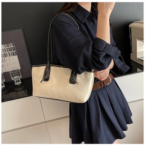 Detail of cream tote bag with dark brown handles and elegant metal knot accents